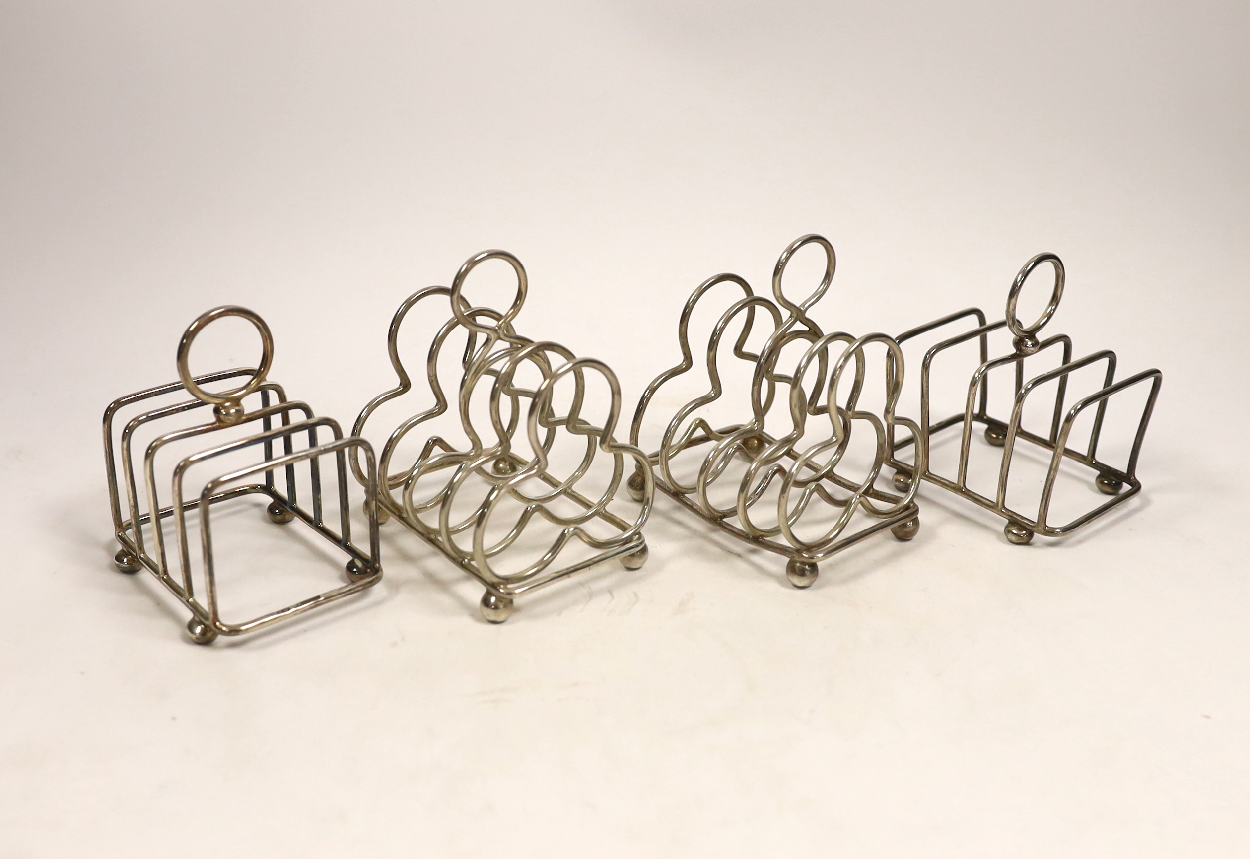 Two pairs of silver five bar toast racks, Lee & Wigfull, Sheffield, 1904 and cusped shaped, London, 1904, tallest 10cm.